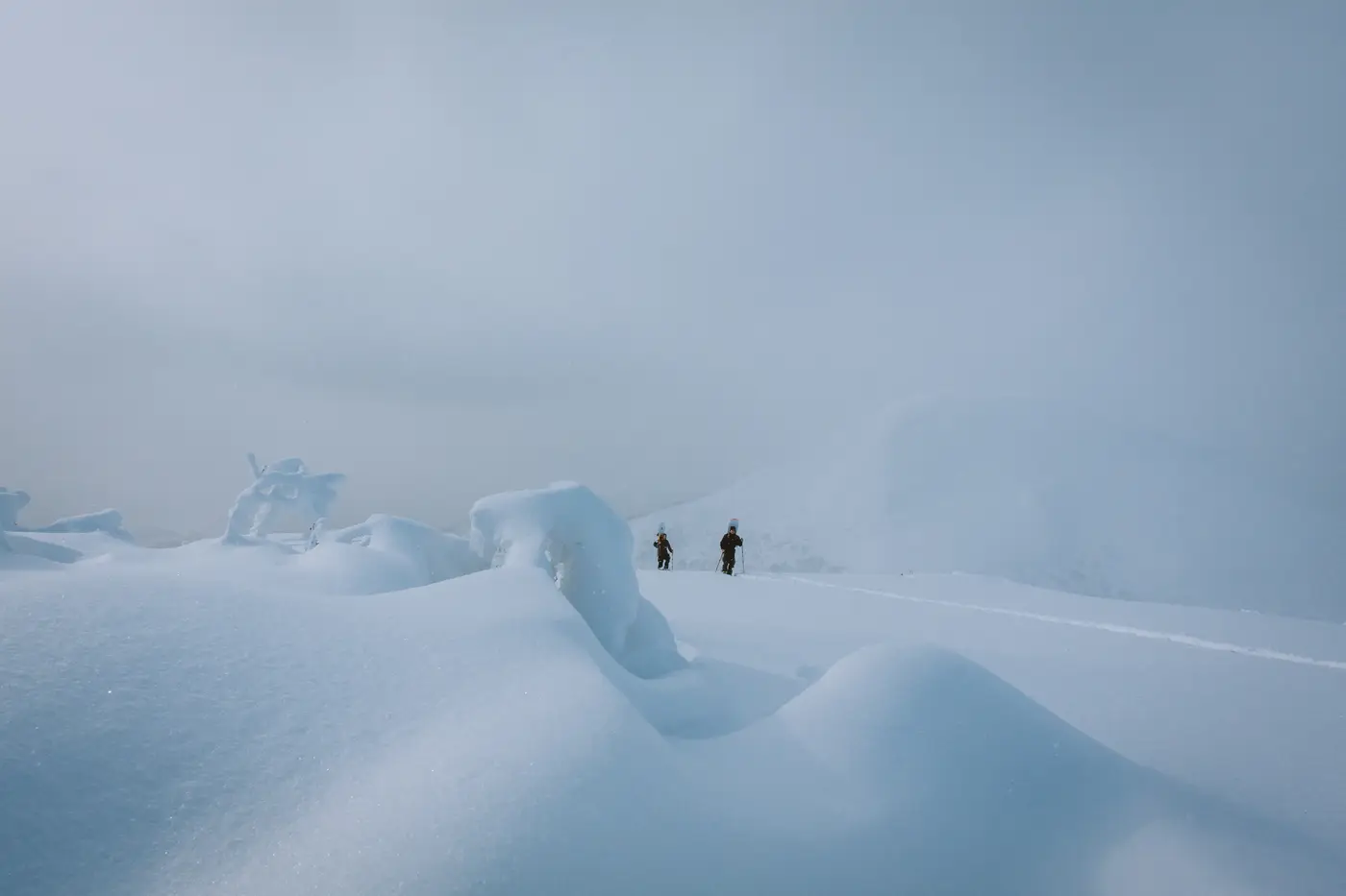 Due rider che camminano nella nebbia fra i gobboni di neve